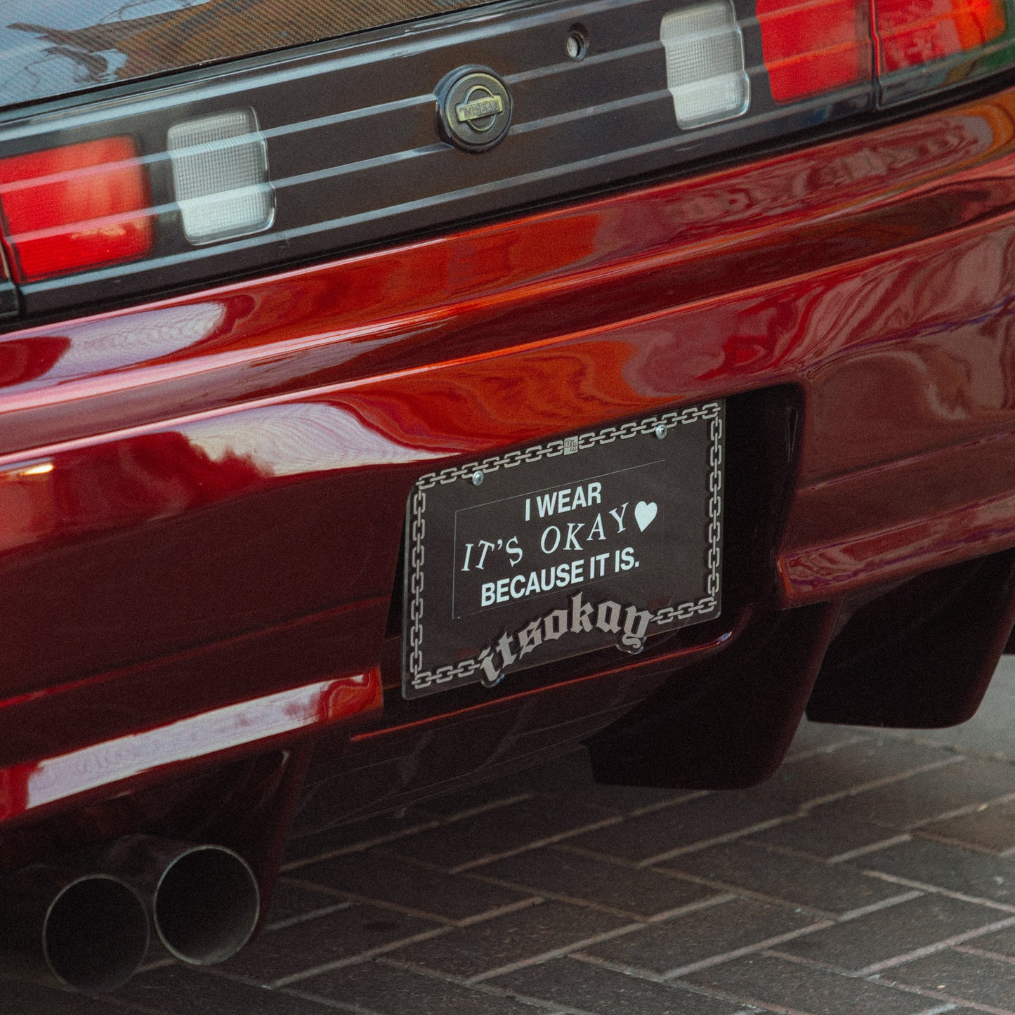 Red car with a personalized license plate on a brick road (Itsokay Branding)