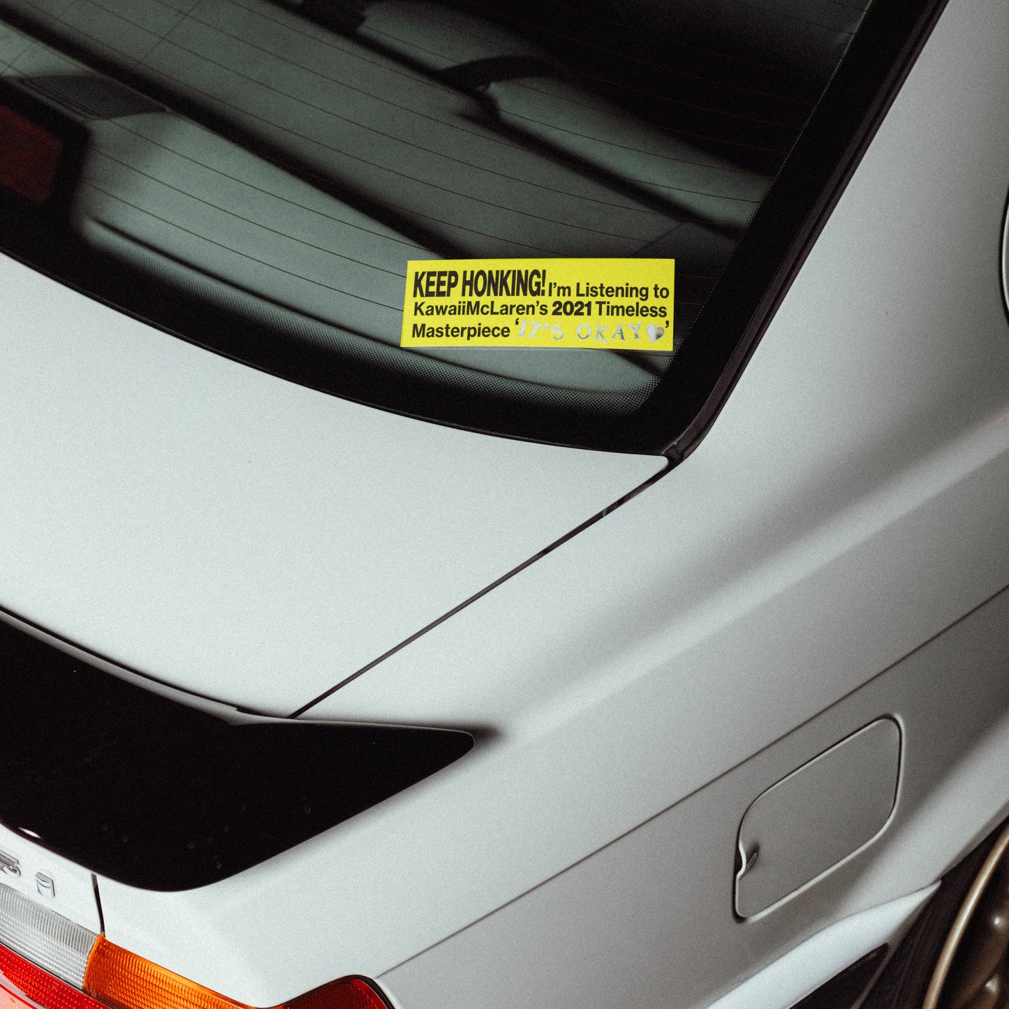 Car rear window with a yellow sticker on a white car (Itaokay)
