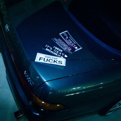 Close-up of a car's front bumper with visible stickers at night. Itsokay