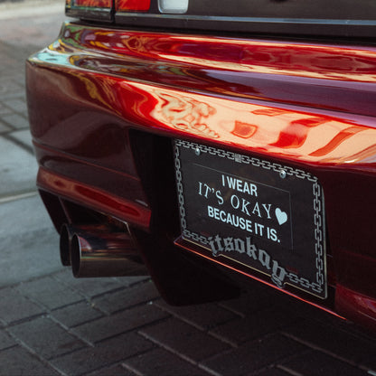 Car tail light with a message decal on a pavement background. Itsokay