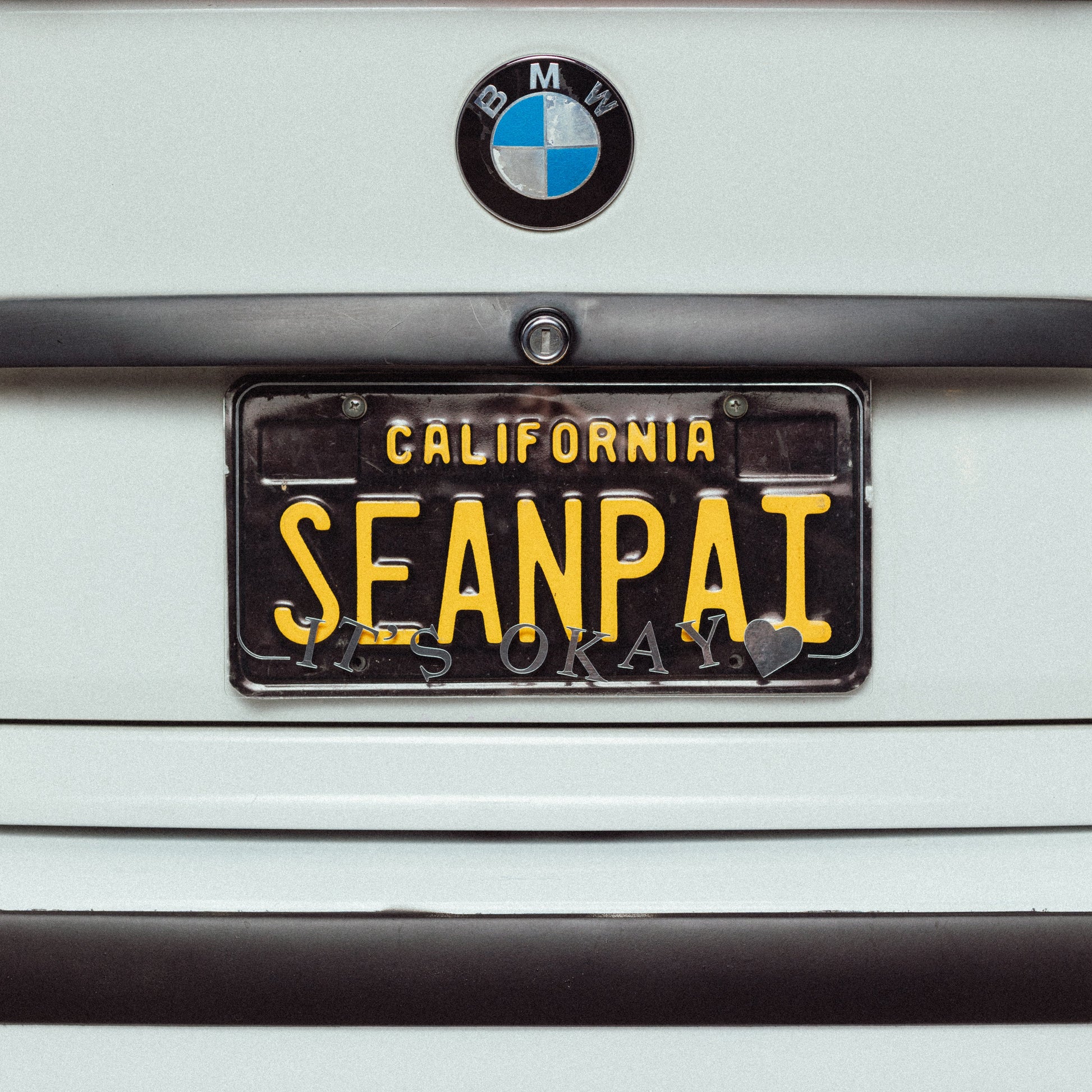 BMW car with a license plate cover  that says 'ITSOKAY'