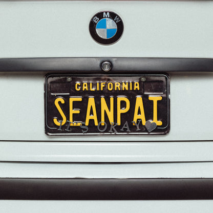 BMW car with a license plate cover  that says 'ITSOKAY'