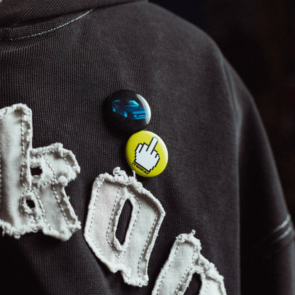 Black hoodie with decorative text and pins on a dark background