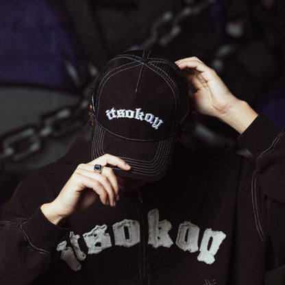 Person wearing a black cap and jacket with 'itsokay' branding.